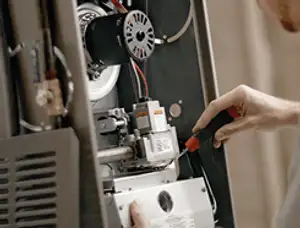 Furnace repair technician inspecting internal components and wiring in Cape Coral, FL