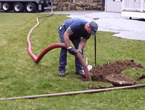 Septic pumping technician servicing a residential septic tank with a vacuum hose in Cape Coral, FL