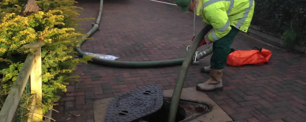 Septic tank cleaning technician servicing a septic tank with a vacuum hose in Cape Coral, FL