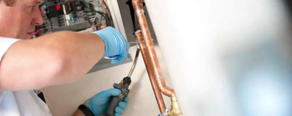 Water heater repair technician testing copper pipe connections and controls in Cape Coral, FL